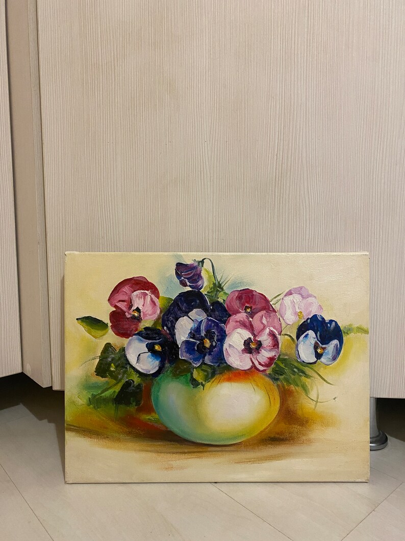 May include: A painting of a bouquet of purple, pink, and white pansies in a green vase. The pansies are arranged in a loose, natural style, and the vase is simple and elegant. The background is a soft, cream color.