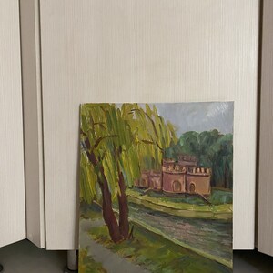 May include: A painting depicting a landscape with a river, a small castle, and a weeping willow tree. The castle is painted in shades of pink and brown, and the willow tree has green leaves. The river is a light blue colour.