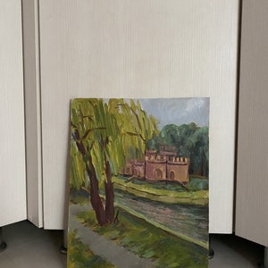 May include: A painting depicting a landscape with a small castle in the background, a river in the foreground, and a weeping willow tree on the left side of the painting.