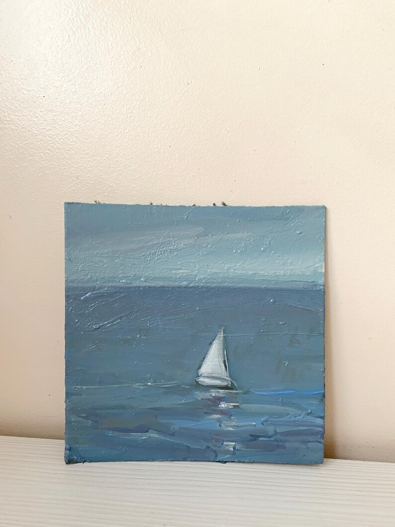 May include: A painting of a sailboat on a blue ocean with a light blue sky in the background.