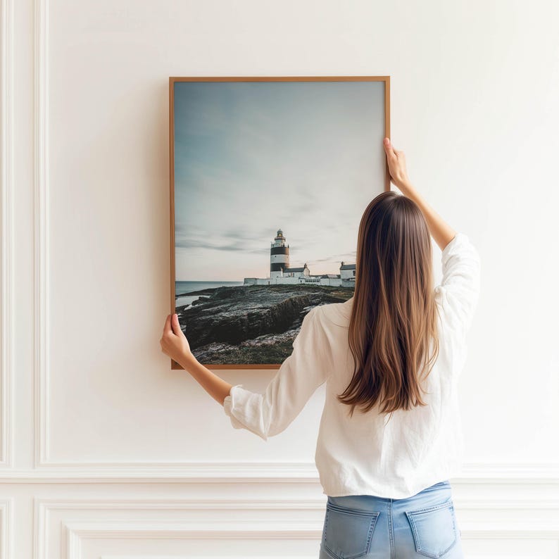 a woman holding up a picture of a lighthouse