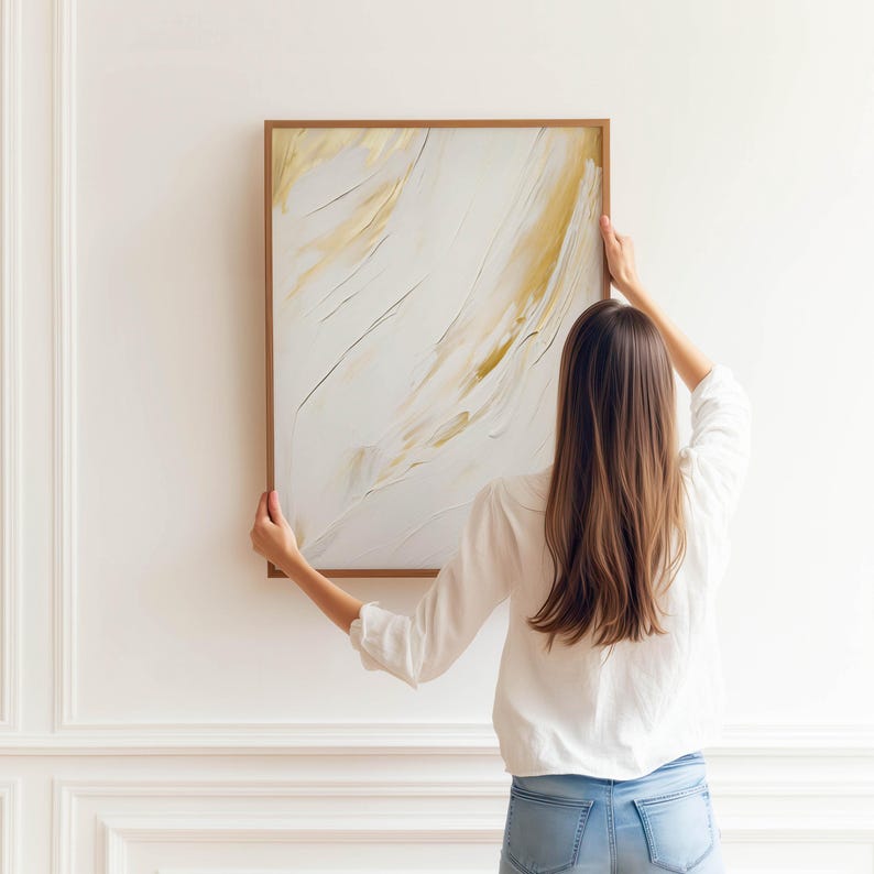 Poster-style wall art featuring gold brush-like graphic in neutral living room.