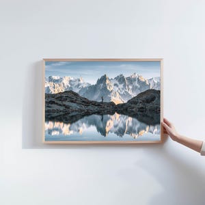 a person holding up a picture of a mountain range