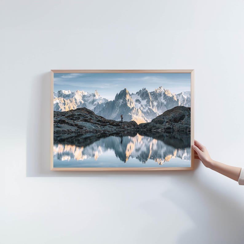 a person holding up a picture of a mountain range