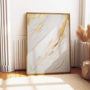 Gold and white abstract print propped against wall near pampas decor.