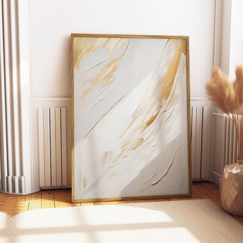 Gold and white abstract print propped against wall near pampas decor.
