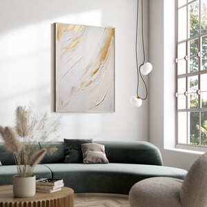 Abstract art print with gold strokes styled above green sofa in daylight.