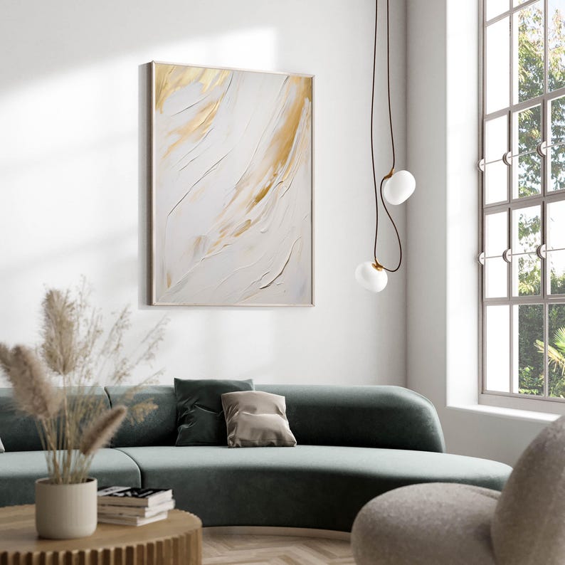 Abstract art print with gold strokes styled above green sofa in daylight.