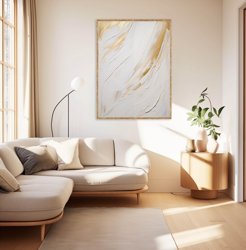 Minimalist gold and white wall print above cream couch with plant.