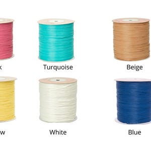 May include: Six spools of decorative ribbon in various colors: pink, turquoise, beige, yellow, white, and blue. Each spool is labeled with its color name. The ribbon is tightly wound on cardboard cores.