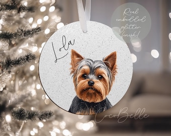 May include: Round Christmas ornament featuring a Yorkshire Terrier dog portrait. The ornament has a glitter finish and the name "Lola" in script. The text "Real embedded glitter finish!" is also visible.