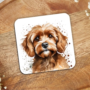 May include: Square coaster with a watercolour illustration of a Cavapoo dog. The dog has brown and white fur, with a gentle expression. The background has brown watercolour splatters.