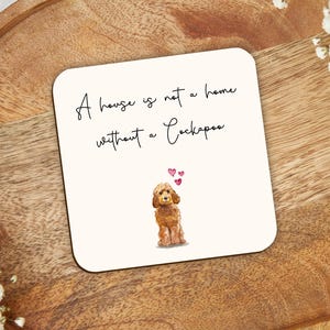May include: Cream-coloured square coaster featuring the text "A house is not a home without a Cockapoo" and a watercolour illustration of a Cockapoo. Set on a wooden tray.