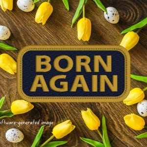 May include: A blue and gold embroidered patch with the text "BORN AGAIN" surrounded by yellow tulips and speckled eggs on a brown wooden background.