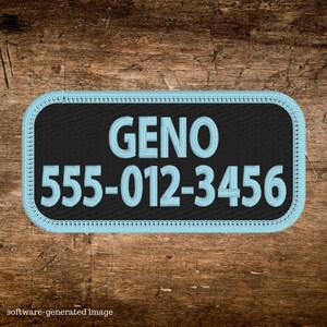 May include: A rectangular black patch with rounded corners, featuring the name "GENO" and a phone number in light blue stitching. The patch has a light blue border and is set against a wooden background.