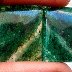 Puede incluir: Dos piedras preciosas cuadradas de color verde vibrante, con una mezcla de tonos claros y oscuros. Las piedras tienen un aspecto natural y orgánico con un brillo sutil. La superficie presenta patrones verdes y blancos.