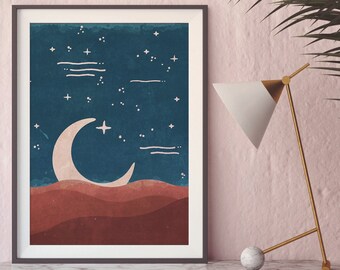 May include: A framed print with a crescent moon and stars on a blue background. The moon is white and the stars are white with a yellow center. The background is a dark blue with a watercolor effect. The bottom of the print is a red and orange landscape.