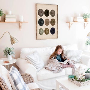 May include: A framed print of nine brown, gray, and blue circles arranged in a grid. The circles are all the same size and are evenly spaced. The print is hanging on a white wall in a living room.