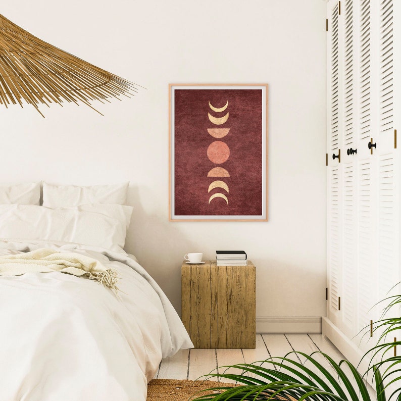 May include: A minimalist art print with a red background and gold moon phases and a sun in the center.