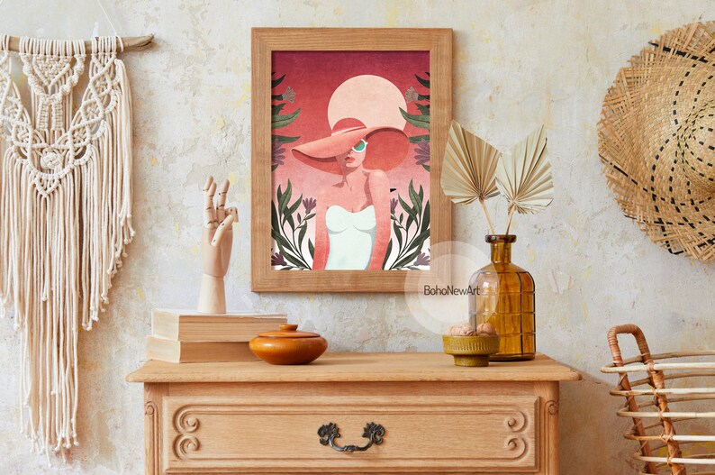 May include: A framed illustration of a woman wearing a large pink hat and sunglasses, standing in front of a pink and orange sunset with green foliage. The text "BohoNewArt" is at the bottom of the image.