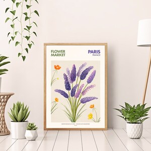 May include: A framed botanical illustration of purple flowers with green leaves and yellow flowers. The frame is wood with a white mat. The text on the frame reads "FLOWER MARKET PARIS FRANCE".