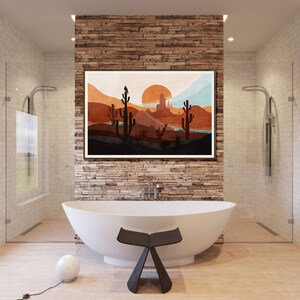 May include: A white freestanding bathtub with a black stool in front of it. A framed print of a desert landscape with a sunset hangs on the wall behind the tub.