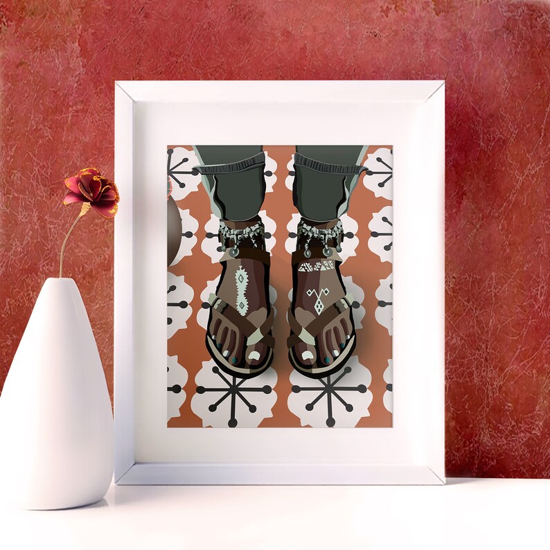 May include: A framed art print featuring an illustration of feet wearing brown sandals with decorative patterns and silver anklets. The sandals are on a patterned orange and white background. A white vase with a red flower is in the foreground.