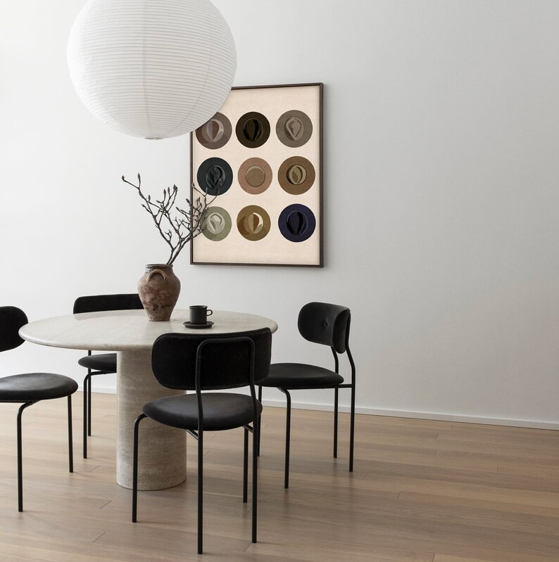 May include: A white dining table with a round top and a single pedestal base. Four black chairs with upholstered seats surround the table. A framed print of nine colorful circles hangs on the wall behind the table.
