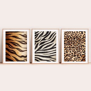 Puede incluir: Tres impresiones enmarcadas con diseños de estampado animal. Las impresiones presentan un patrón de rayas de tigre, un patrón de rayas de cebra y un patrón de manchas de leopardo. Las impresiones son todas en tonos de marrón, negro y blanco.