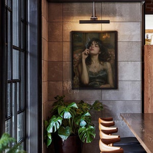 May include: A painting of a woman with dark hair, wearing a dark blue dress, holding a cigarette, hanging on a gray wall in a restaurant setting. There is a potted plant in the corner and a wooden table with chairs in the foreground.