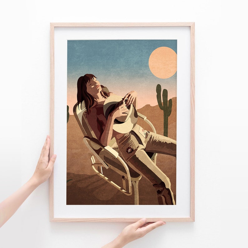 Peut inclure: Une femme v&ecirc;tue d'une chemise brune et d'un jean est assise sur une chaise blanche dans un paysage d&eacute;sertique. Elle tient un chapeau blanc dans ses mains. Le soleil se couche &agrave; l'arri&egrave;re-plan et il y a un cactus au premier plan.