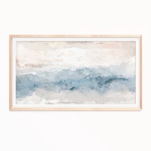 May include: Abstract watercolor art print in a light wood frame. The artwork features a blend of blue, beige, and white hues, creating a serene, cloud-like effect. The rectangular framed art is suitable for home decor.