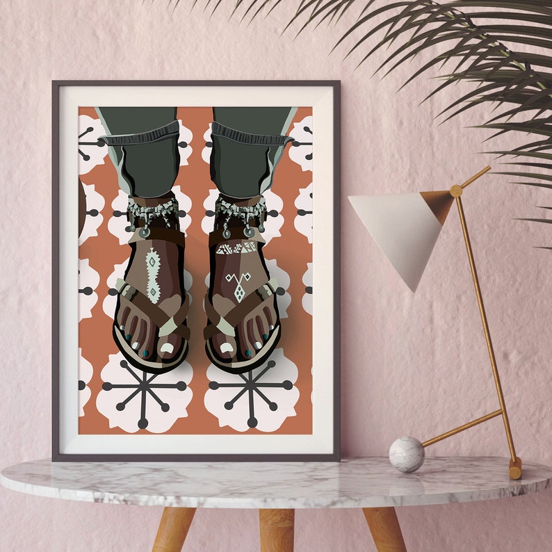May include: Framed art print featuring a stylized illustration of feet wearing brown sandals with decorative straps and silver anklets. The sandals have white and turquoise accents. The background is a pattern of white flowers on a terracotta-colored surface.