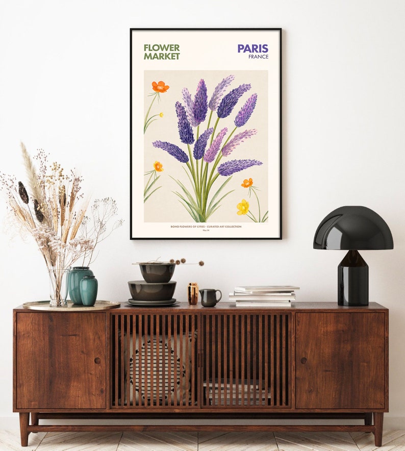 May include: A vintage botanical illustration of purple flowers with yellow flowers in the background. The illustration is framed and hanging on a white wall above a wooden cabinet. The text "FLOWER MARKET" and "PARIS FRANCE" is printed at the top of the illustration.