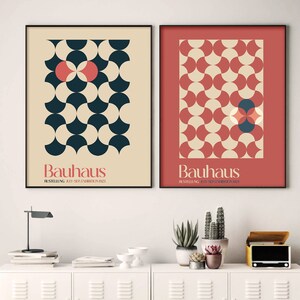 Pode incluir: Dois cartazes Bauhaus com padrões geométricos em vermelho, creme e azul. O texto nos cartazes diz "Bauhaus" e "Ausstellung, julho-setembro de 1923".