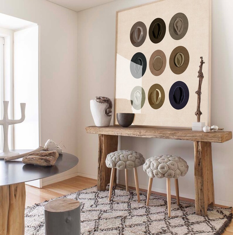 May include: A wooden console table with two round, gray knitted poufs. The table has a rustic, weathered look and is decorated with a framed print of nine abstract circles in various shades of brown and gray.