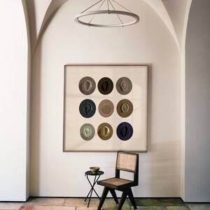 May include: A framed print of nine abstract circles in various shades of brown, gray, and beige. The circles are arranged in a 3x3 grid. The print is hanging on a white wall in a room with a vaulted ceiling.