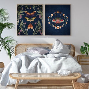 May include: Two framed prints with a dark blue background and floral designs featuring butterflies. The prints are hanging on a white wall above a light wood bed frame with a white duvet and pillows.