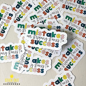 Puede incluir: Un mont&oacute;n de pegatinas coloridas con el texto "Mistakes are stepping stones to success" en ellas. Las pegatinas son blancas con un borde redondeado y tienen un dise&ntilde;o colorido con una mezcla de rosa, amarillo, verde y azul.