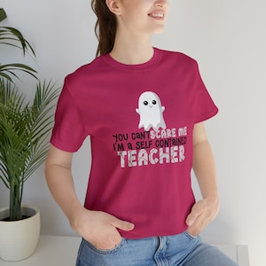 May include: A pink t-shirt with a white ghost graphic and the text "You can't scare me I'm a self contained teacher".