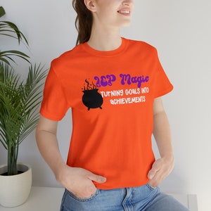 May include: Orange t-shirt with a black cauldron and purple text that reads "IEP Magic Turning Goals Into Achievements".