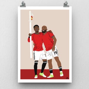 May include: A poster print featuring a digital illustration of two soccer players in red jerseys and white shorts, celebrating a victory. One player holds a flag. The artwork has a minimalist style with a beige background and a red base.