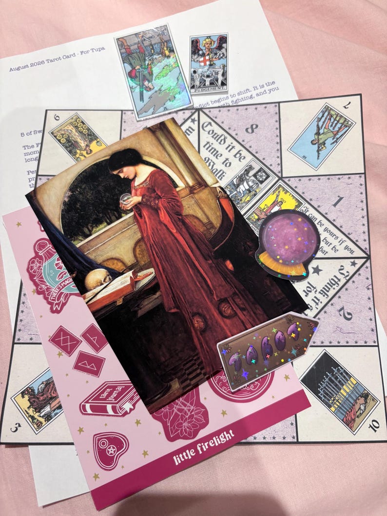 Pu&ograve; includere: Una collezione di articoli a tema tarocchi che include un tabellone di gioco stampato con sezioni numerate, una carta rettangolare con una donna in abito rosso che tiene una sfera di cristallo, un adesivo olografico e un piccolo adesivo a forma di freccia.