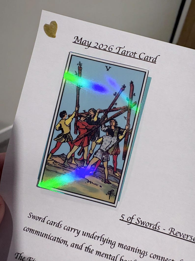 Pu&ograve; includere: Una carta bianca con il testo May 2026 Tarot Card e 5 of Swords - Reverse. Al centro &egrave; presente un'illustrazione della carta dei tarocchi Cinque di Bastoni con una sovrapposizione olografica che mostra cinque figure che tengono bastoni. Un piccolo cuore dorato &egrave; in alto a sinistra.