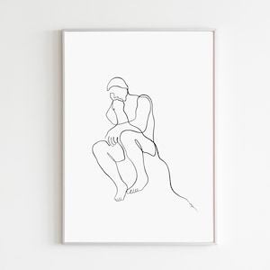 May include: Minimalist black line art print of a person in a seated, contemplative pose. The artwork features a continuous line drawing on a white background, framed in a silver-colored frame. The figure is depicted with simple, elegant strokes.
