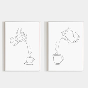 以下が含まれることがあります： 2つの額入りミニマリストラインアートプリント。1つはカップに注ぐコーヒーメーカー、もう1つはマグカップに注ぐティーポットを示しています。どちらも白い背景に黒い線画で、ピンクのボーダーが付いています。