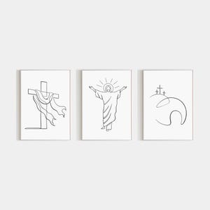 May include: Three framed minimalist line art prints. The prints depict religious themes: a cross with draped fabric, a figure with outstretched arms and a halo, and three crosses on a hill. The art is in black on a white background.