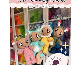 May include: The image showcases four crochet dolls: Buggy, Astro, Flower, and Woodland. The dolls are in pink, teal, yellow, and green. The text "The Whimsy Babies" and "Kouzi Krafts" are visible. The background includes shelves filled with colorful yarn.