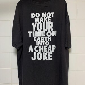May include: Black t-shirt with white text that reads "Do not make your time on earth into a cheap joke."