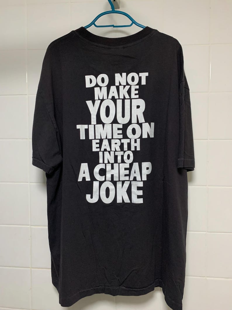 May include: Black t-shirt with white text that reads "Do not make your time on earth into a cheap joke."